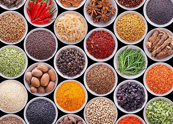 Assorted whole spices and seeds in white bowls